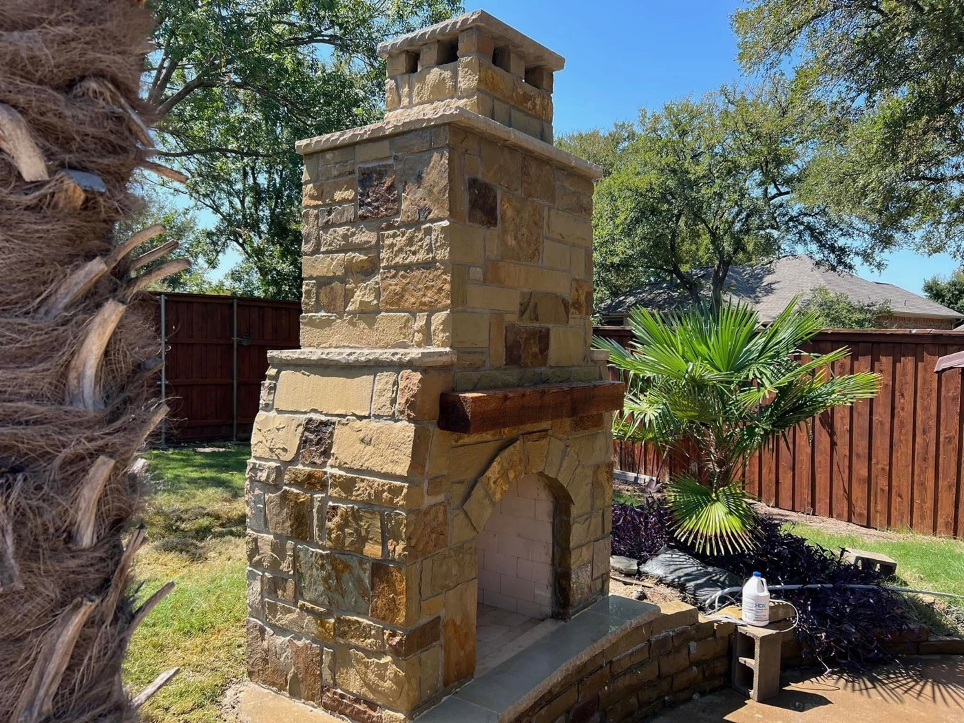 Tall stone outdoor fireplace with cedar mantel