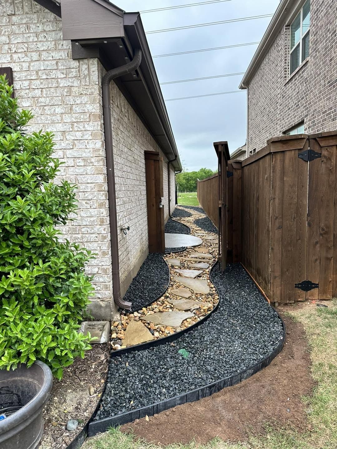 River rock drainage path curving along a side yard