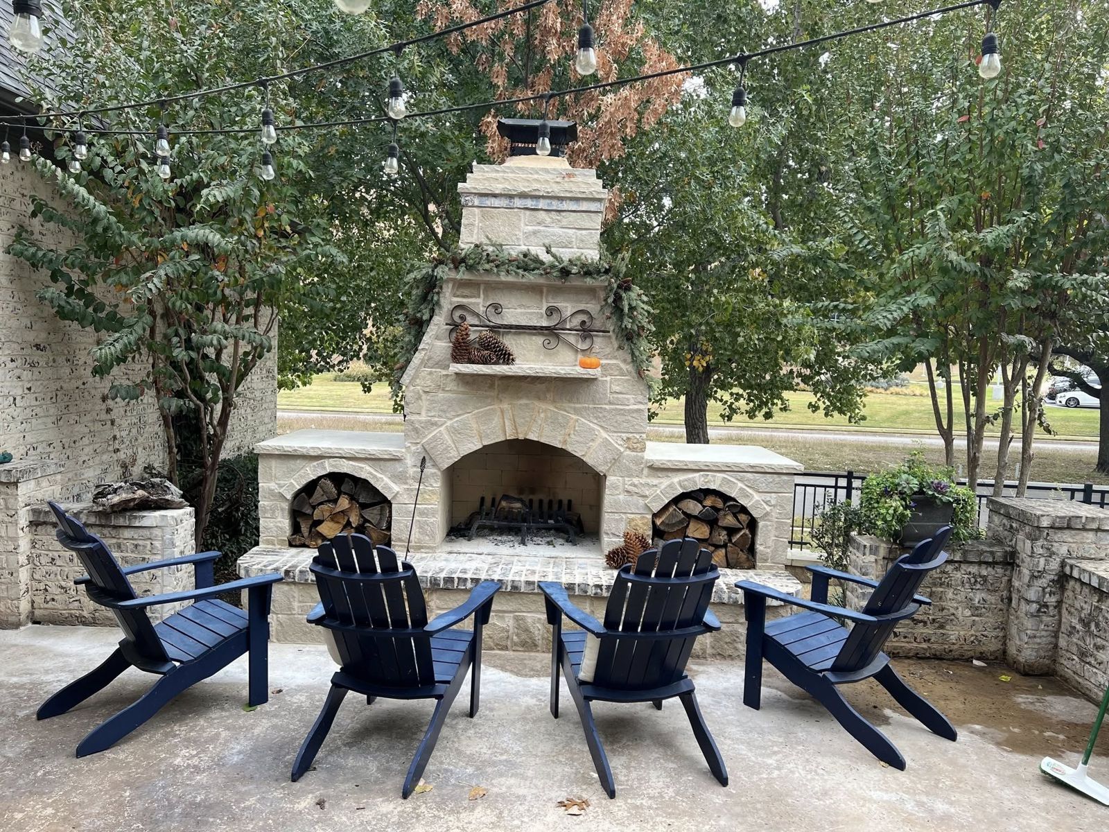 Large stone outdoor fireplace with seating and string lights