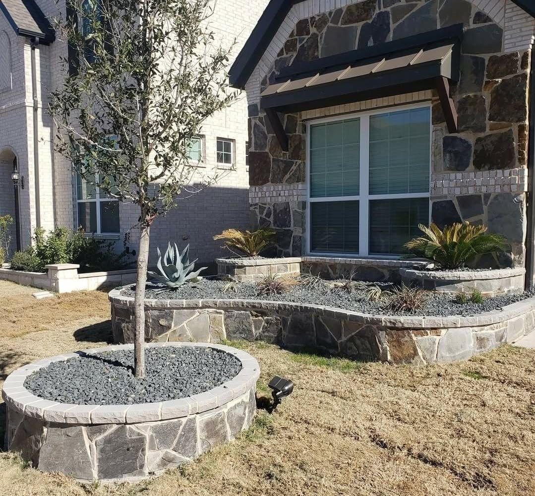Stone raised planter beds and matching tree ring across a front yard