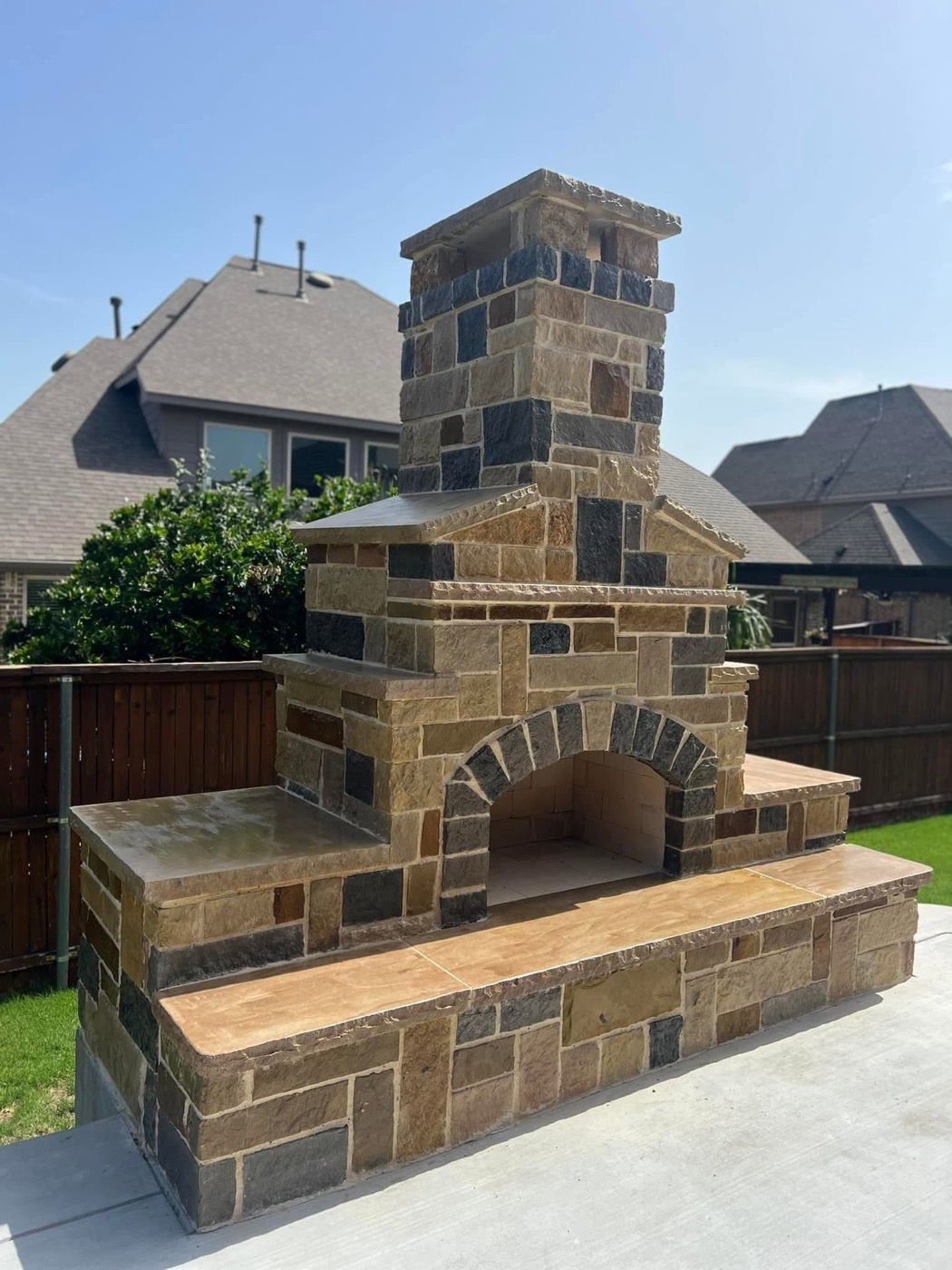 Custom stone outdoor fireplace with hearth benches in DFW