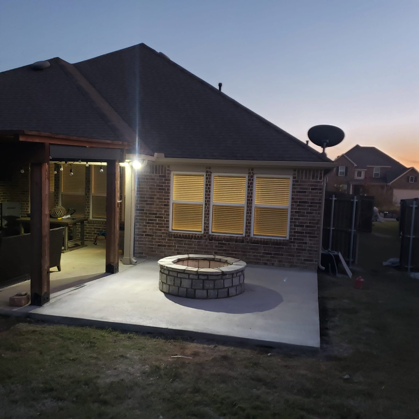 Round stone fire pit on a concrete patio lit at dusk