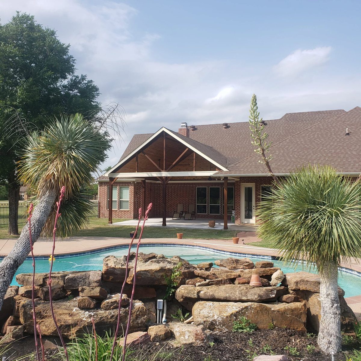 Pool with a stacked boulder waterfall beside a covered patio